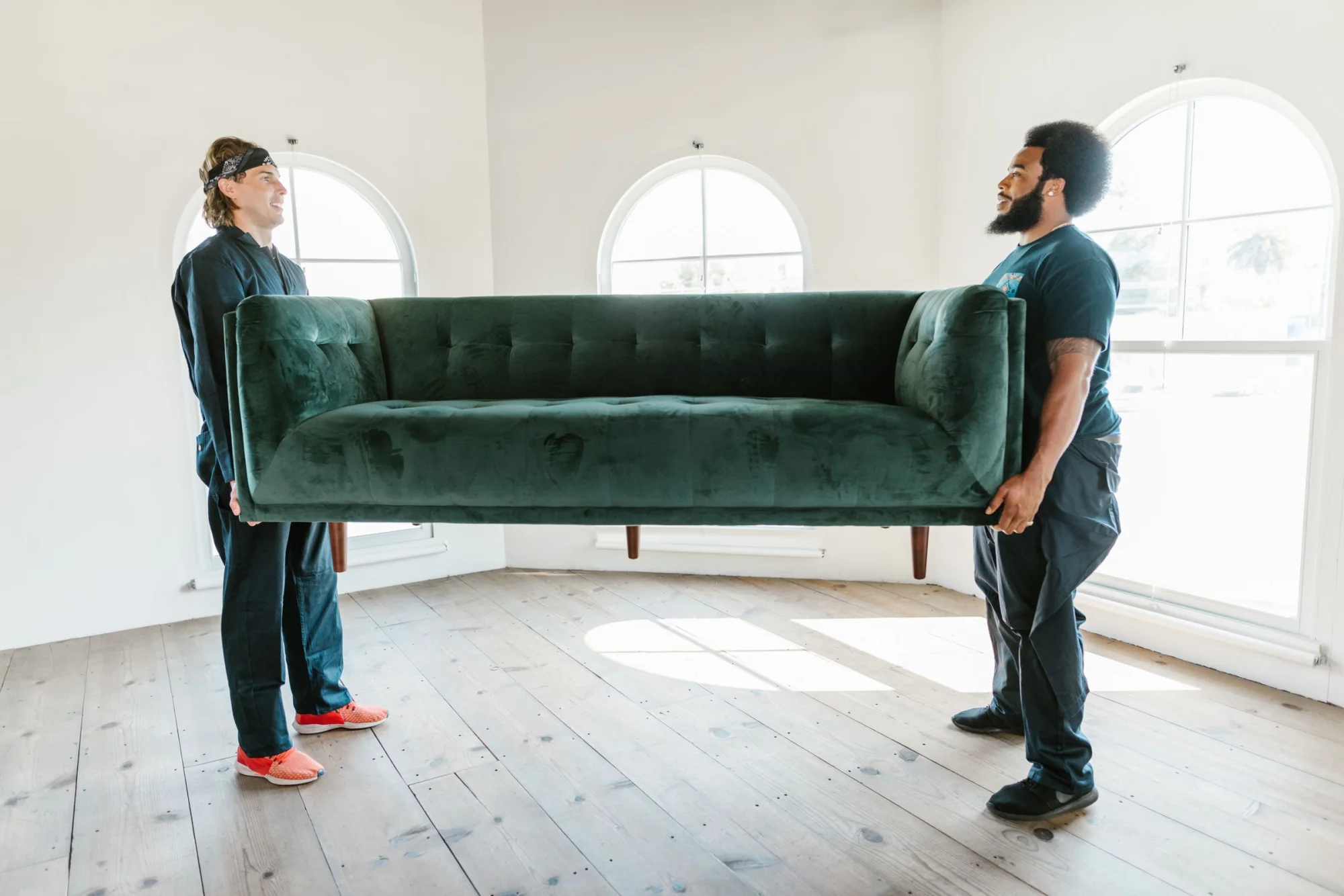 Two professional movers carrying a sofa inside a home